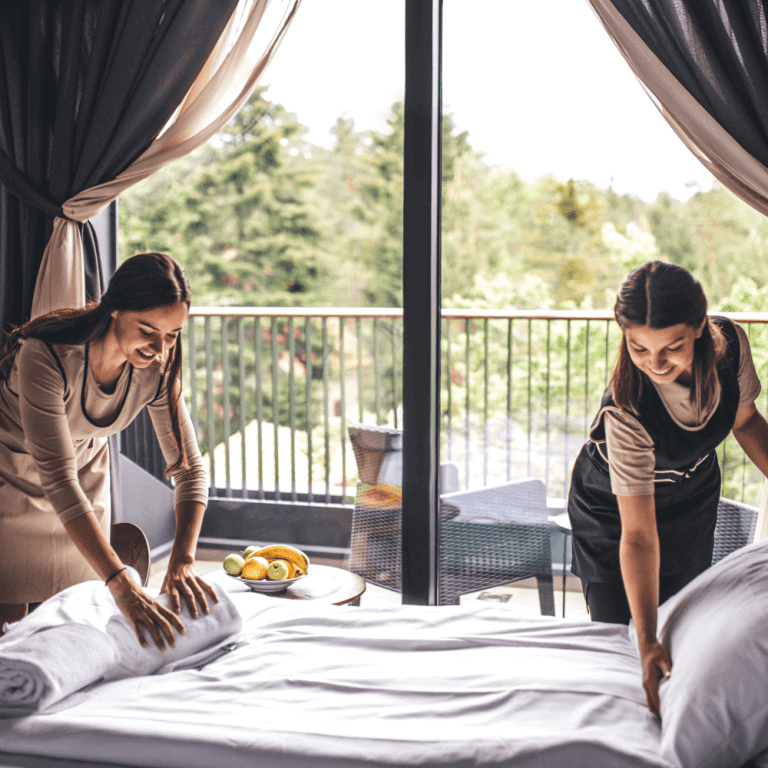 Two day porters work together to make a hotel bed
