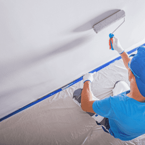 A professional painter using a roller to coat a wall in white paint